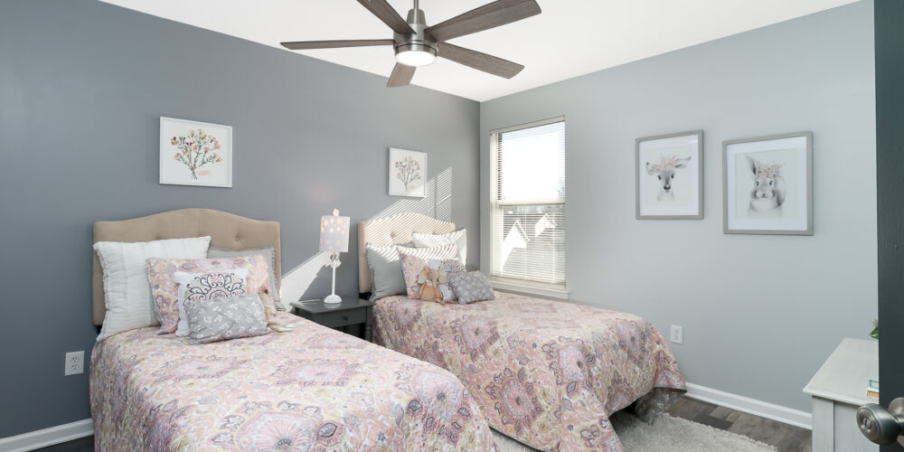 Kids bedroom of a staged St. Charles, MO home, with two twin beds and floral artwork