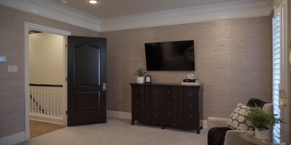 Still 2025-10-20 181133_1.12.1 Alternative view of master bedroom in a Clayton, MO home. There is a rich brown dresser drawer adorned with decorative pieces and a small green fern.