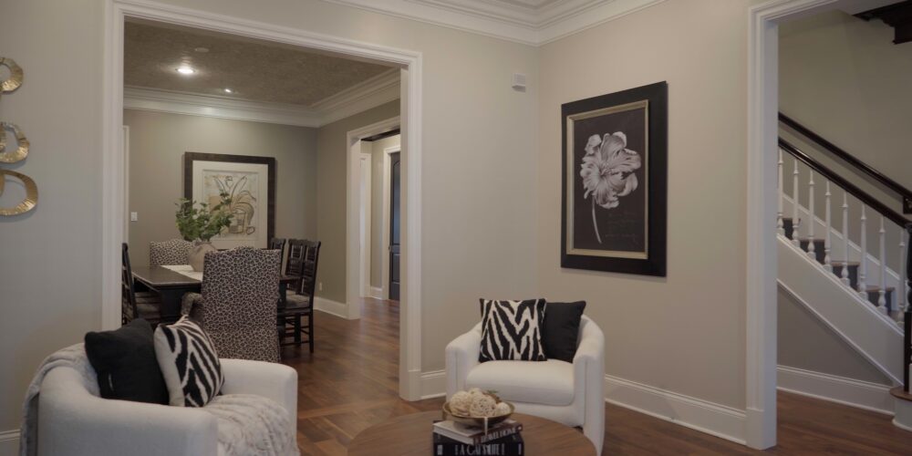 Still 2025-10-20 181133_1.2.1 The living room of a home for sale in Clayton, MO, which has been staged with two armchairs featuring black and white striped pillows.